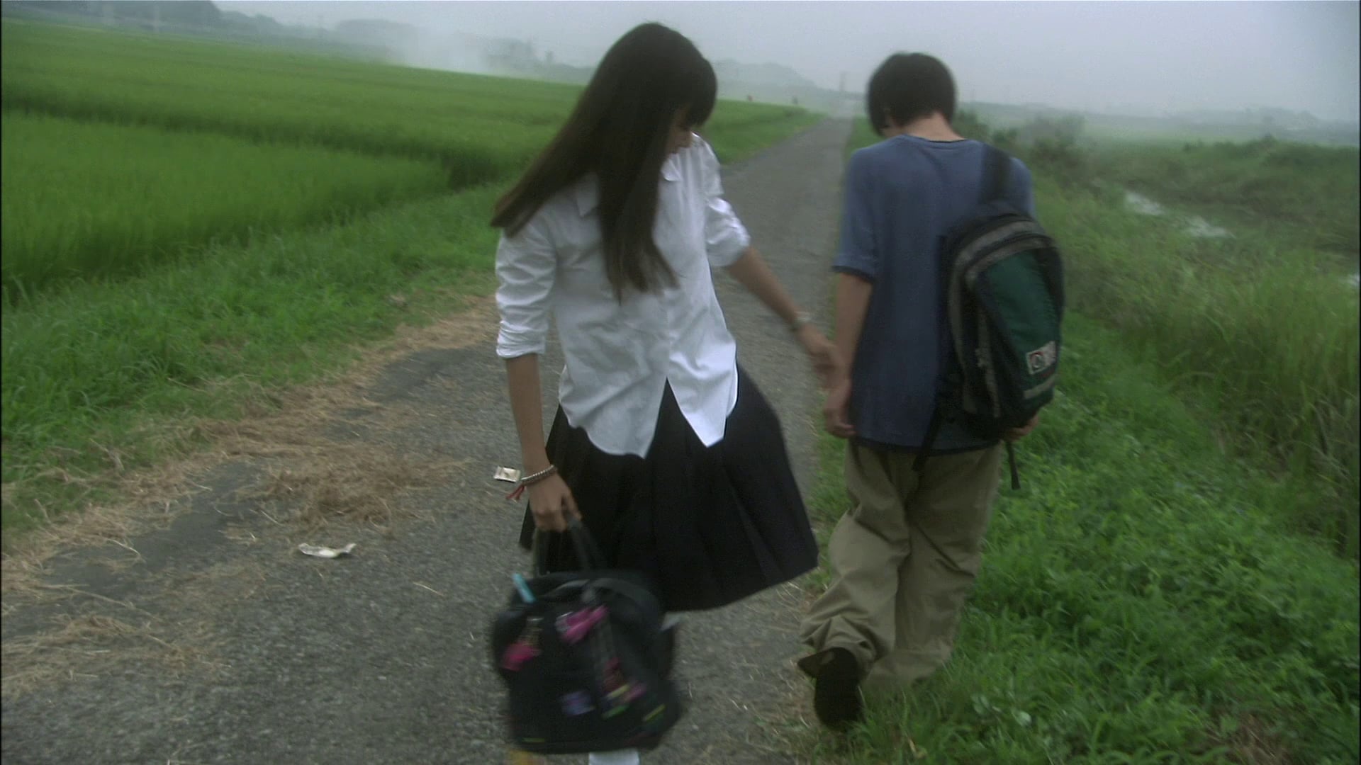Two school students sharing a moment on a narrow country road