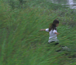 Animated scene from the film depicting Tsuda spinning with outstretched arms in the green field